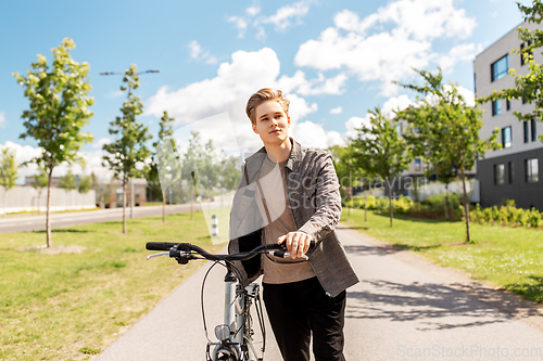 Image of young man with bicycle walking along city street