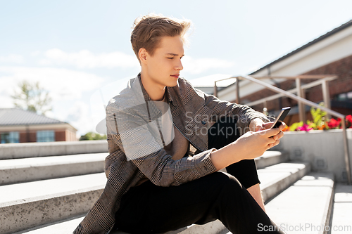 Image of teenage boy using smartphone in city