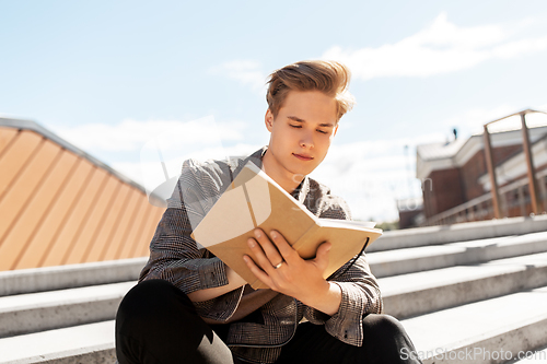 Image of young man with notebook or sketchbook in city
