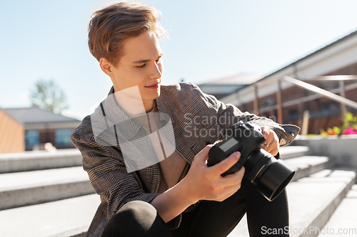 Image of young man with camera photographing in city