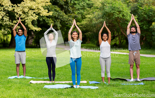 Image of group of people doing yoga at summer park