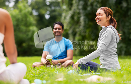 Image of group of people sitting on yoga mats at park