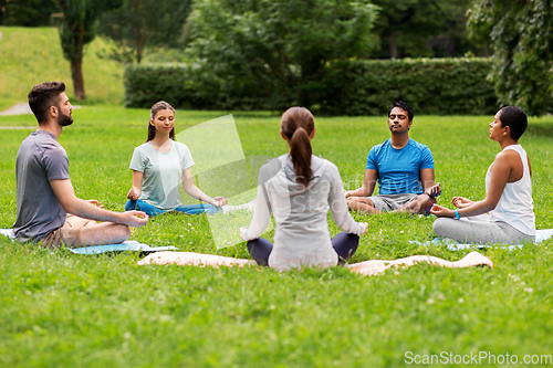 Image of group of people doing yoga at summer park