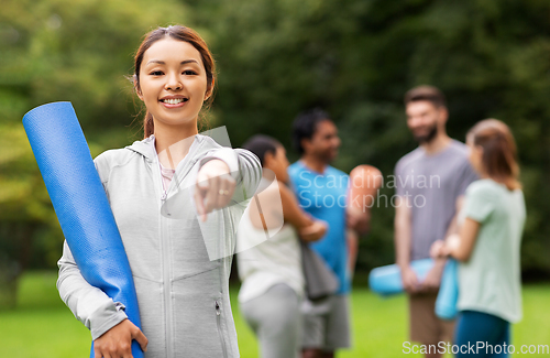 Image of woman with yoga mat pointing finger to camera