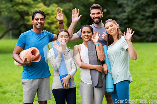 Image of group of happy people with yoga mats at park