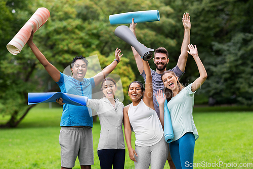 Image of group of happy people with yoga mats at park