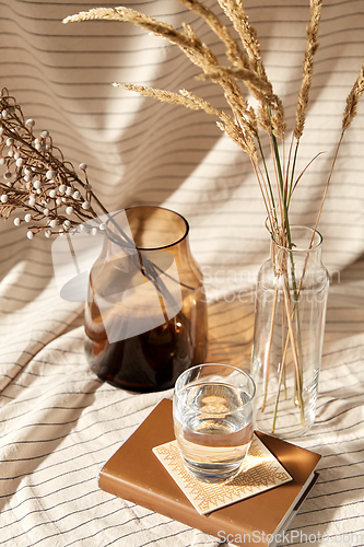 Image of glass of water, decorative dried flowers in vases