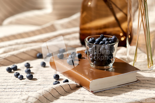 Image of cup of blueberry, book and dried flowers in vases