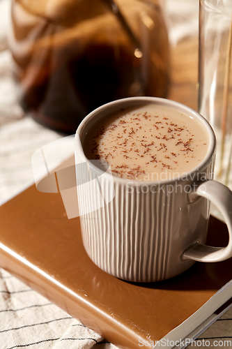 Image of cup of coffee on book and dried flowers in vases