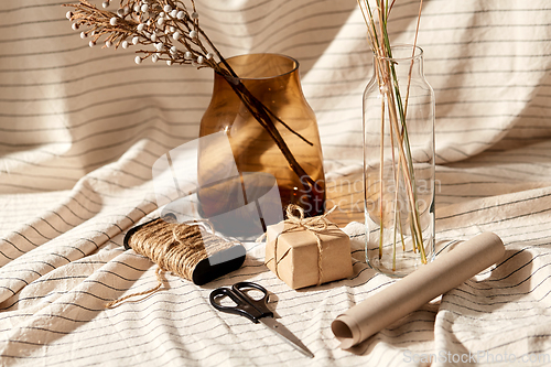 Image of gift wrapping, dried flowers in vases on drapery