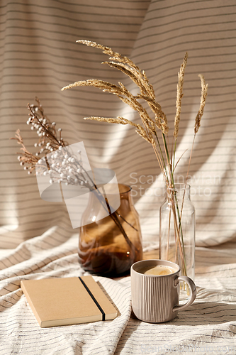 Image of cup of coffee, diary and dried flowers in vases