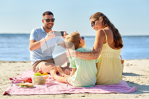 Image of family with smartphone photographing on beach