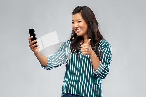 Image of asian woman with smartphone showing thumbs up