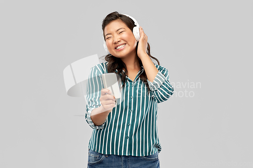 Image of happy asian woman in headphones listening to music