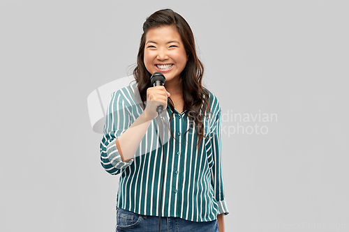 Image of happy asian woman with microphone singing