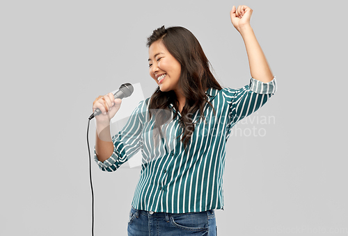 Image of happy asian woman with microphone singing