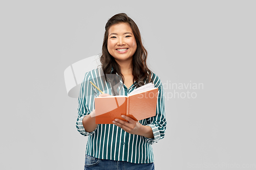 Image of happy asian student woman with diary and pencil