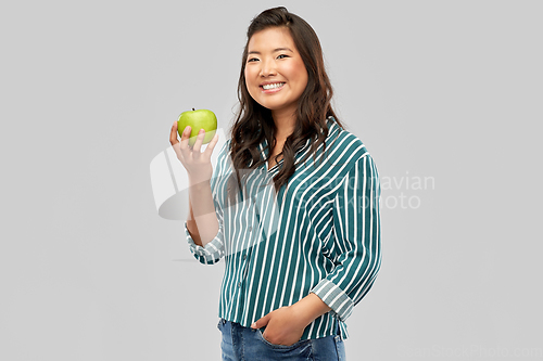 Image of happy smiling asian woman holding green apple