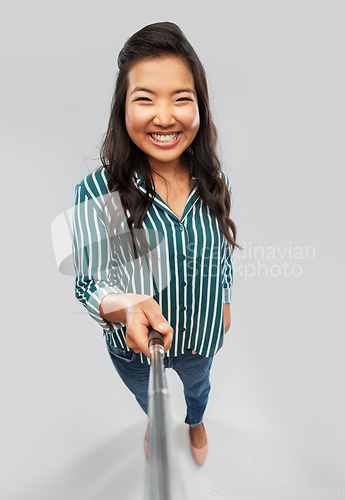 Image of happy asian woman taking picture with selfie stick