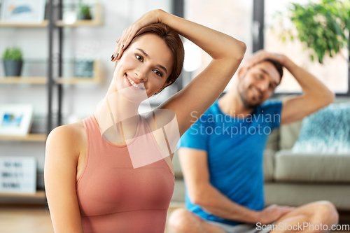 Image of happy couple exercising at home