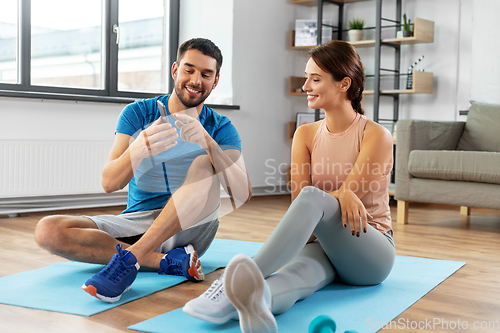 Image of happy couple with smartphone doing sports at home