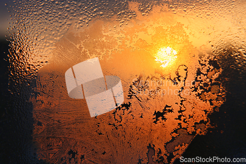 Image of Ice patterns, water drops and sunlight on a window glass