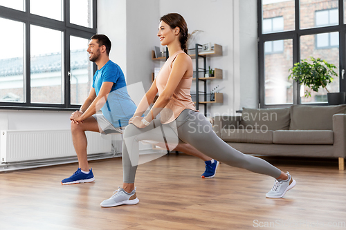 Image of happy couple exercising and doing squats at home