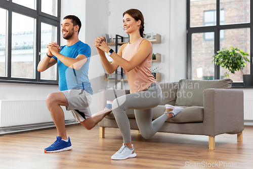 Image of happy couple exercising and doing squats at home