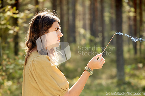 Image of woman or witch performing magic ritual in forest