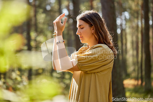 Image of woman or witch performing magic ritual in forest