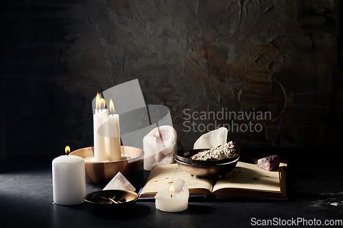 Image of magic book, sage, burning candles and ritual staff