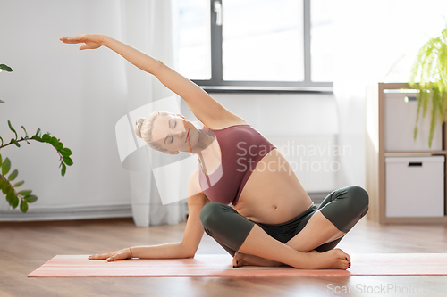 Image of happy pregnant woman doing yoga at home
