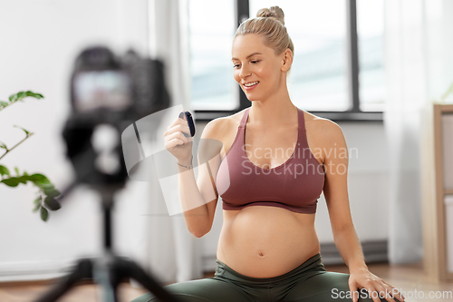 Image of pregnant woman or yoga blogger with camera at home
