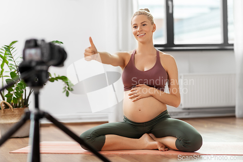 Image of pregnant woman or yoga blogger with camera at home