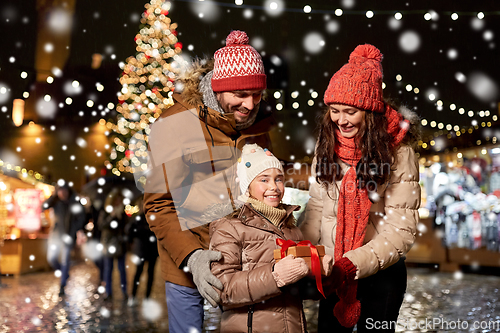 Image of happy family with gift at christmas market in city