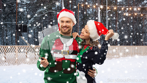 Image of happy couple in christmas sweaters taking selfie