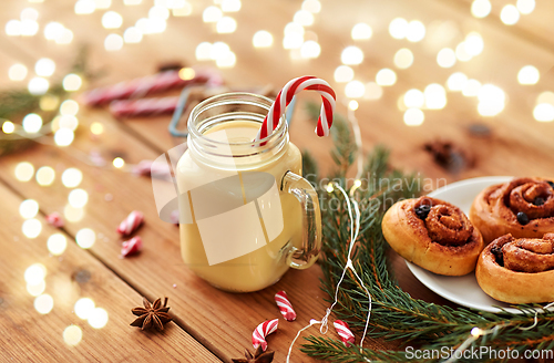Image of eggnog with candy cane in mug and cinnamon buns