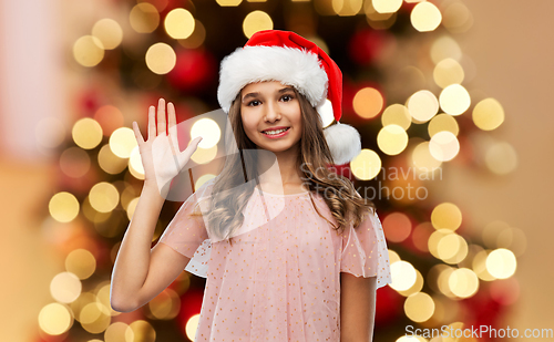 Image of happy teenage girl waving hand on christmas