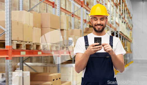 Image of happy male worker with smartphone at warehouse