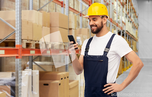 Image of happy male worker with smartphone at warehouse