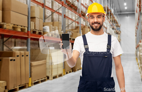 Image of happy male worker with smartphone at warehouse