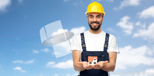 Image of happy male builder holding model of living house