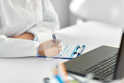 Image of doctor with laptop and medical report at hospital