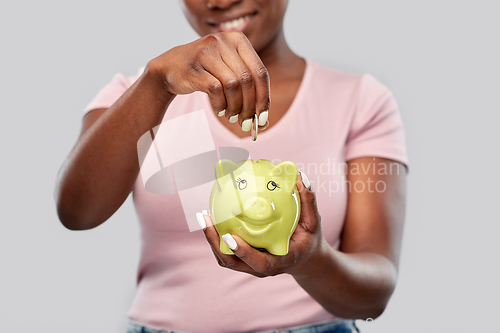 Image of close up of woman with coin and piggy bank