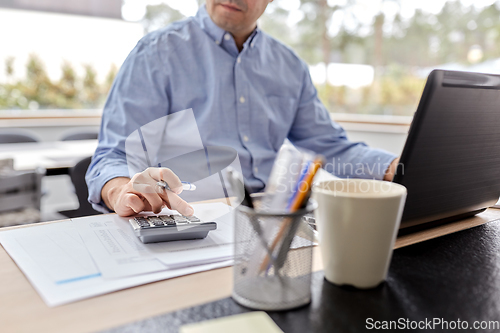 Image of man with calculator and papers working at home