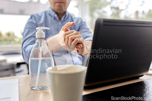 Image of man using hand sanitizer at home office