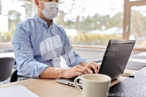 Image of man in mask with laptop working at home office