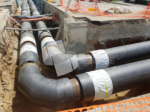 Image of Laying heating pipes in a trench at construction site.
