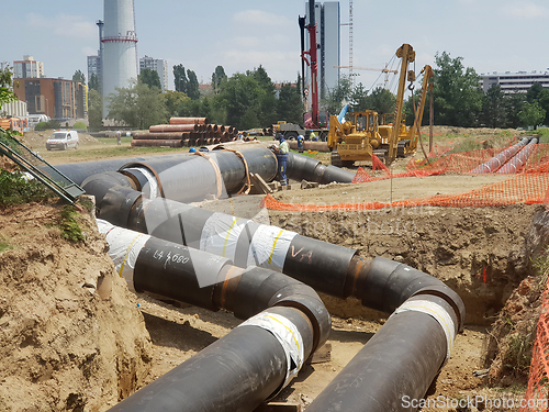 Image of Laying heating pipes in a trench at construction site.