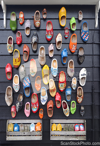 Image of Many multicolored vintage Dutch Klomp shoes on black wood panel 